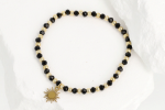 Bransoletka damska na gumce z czarnych koralików i zawieszką słońce – złota stal